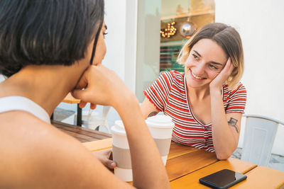 Smiling lesbians enjoying coffee on table