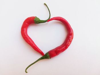 Close-up of red chili peppers over white background