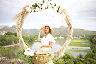 Portrait of smiling young woman standing by wicker basket