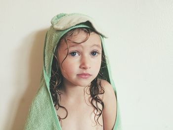 Close-up portrait of wet girl with towel standing against wall at home