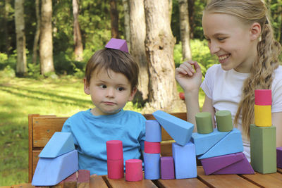 Cute siblings playing with toy blocks outdoors