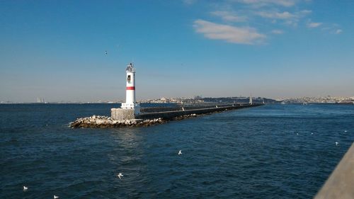 Lighthouse amidst sea against sky