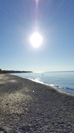 Scenic view of beach against blue sky on sunny day