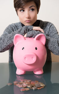 Young woman with piggy bank at table