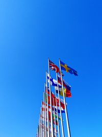 Low angle view of flags against clear blue sky