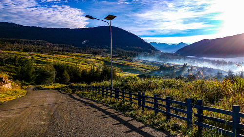 Road by trees against sky