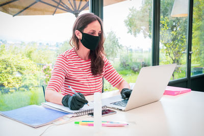 Mature woman wearing mask working at home