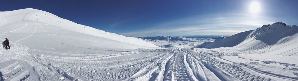 Tire tracks amidst snowcapped mountains against sky