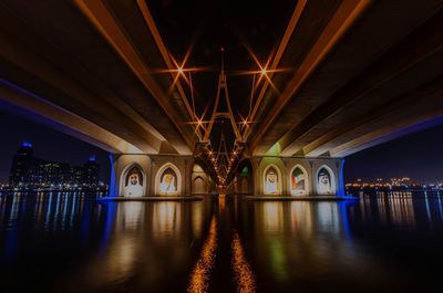 Illuminated bridge over river at night