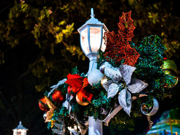 Low angle view of street light with christmas decoration against tree