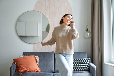 Young woman using mobile phone while sitting at home