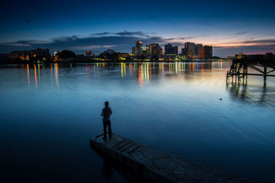 Silhouette man standing by sea against sky during sunset