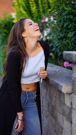 Young woman laughing while holding ice cream cone