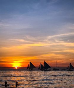 Silhouette sailboats on sea against sky during sunset