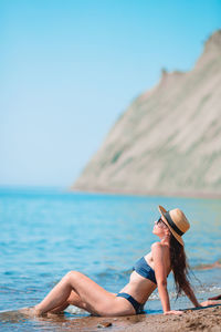 Woman wearing hat against sea against clear sky