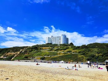 Group of people on beach against blue sky