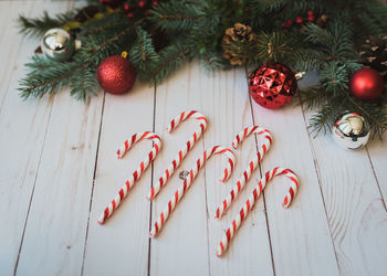 Candy canes on white wood backdrop with christmas decorations.