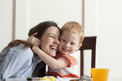 Mother and son embracing while sitting at table