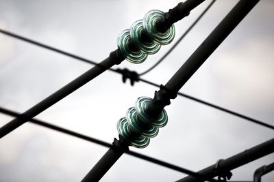 Low angle view of  high voltage line against sky