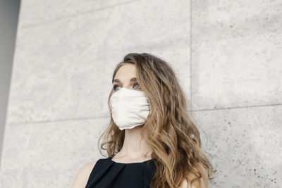 Portrait of young woman standing against wall