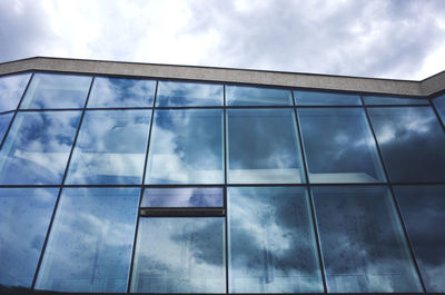 Low angle view of modern glass building against sky during monsoon