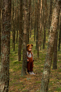 Toddler baby boy in bear bonnet sitting in the woods