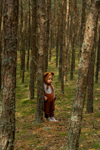 Woman standing by tree trunk in forest