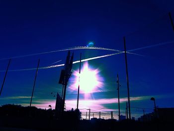 Low angle view of illuminated electricity pylon against sky at night