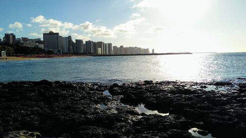 Sea by cityscape against sky