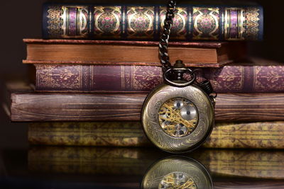 Close-up of pocket watch and stacked books