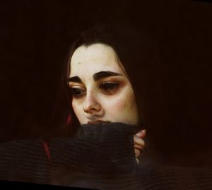 Close-up portrait of young woman against black background