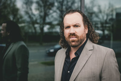 Portrait of businessman standing against window outdoors