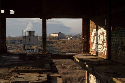 Old buildings in city against sky seen through window