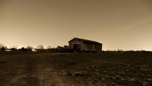 House on field against sky at sunset