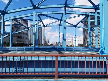 Low angle view of bridge and buildings against blue sky