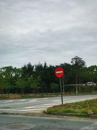 Road sign by street against sky