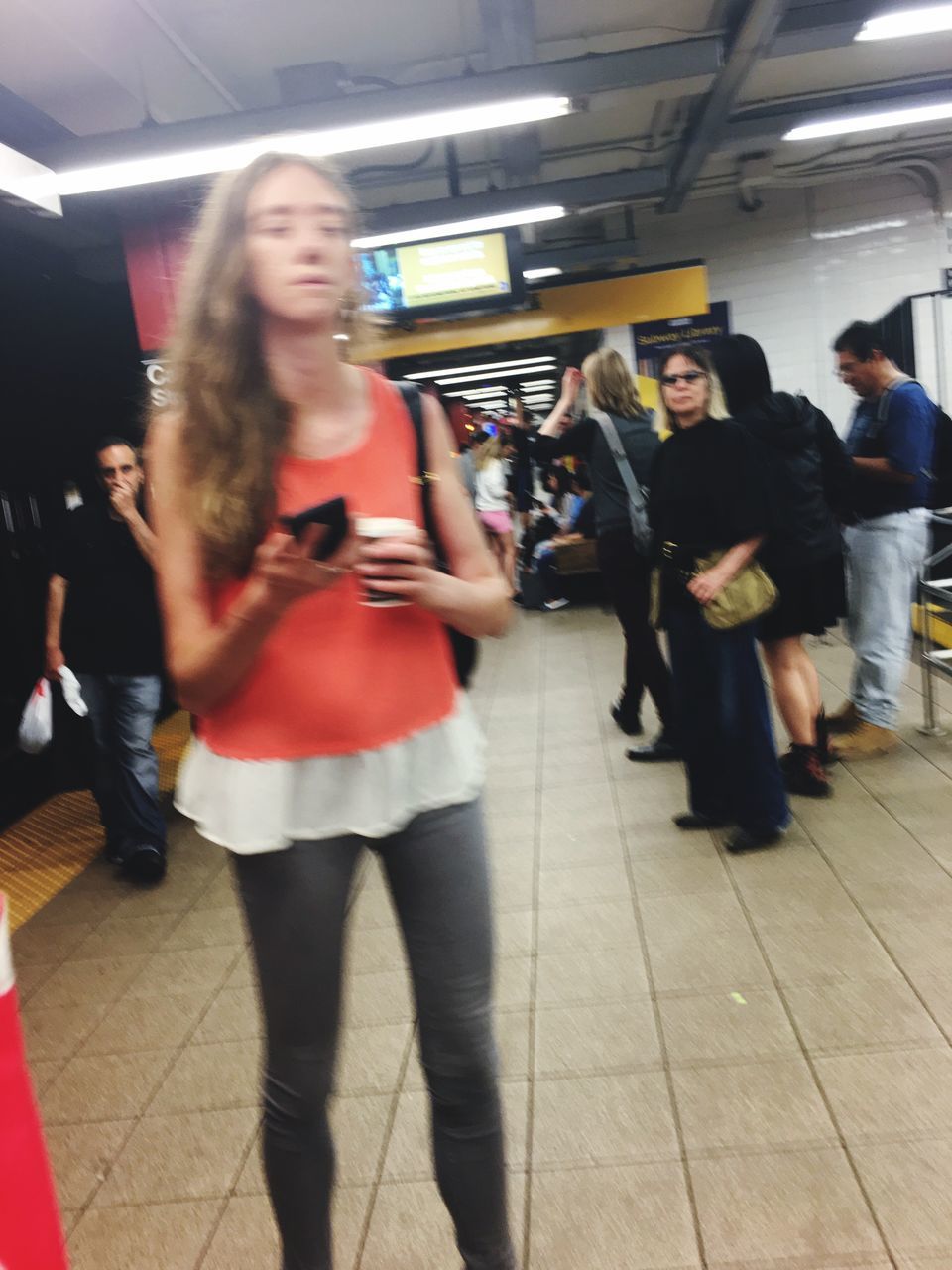 blurred motion, full length, walking, indoors, real people, technology, standing, lifestyles, wireless technology, mobile phone, communication, motion, women, young adult, young women, subway station, illuminated, one person, day, people, adult