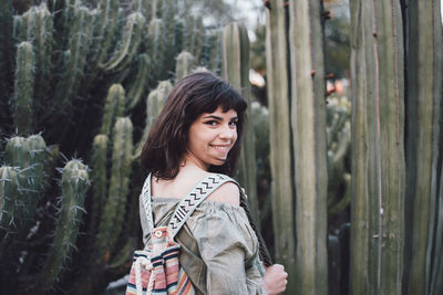 Portrait of smiling young woman standing against plants