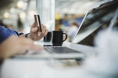 Cropped image of businessman using credit card and laptop at airport lobby