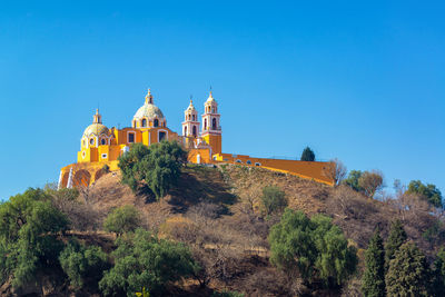 Low angle view of our lady of remedies church against clear blue sky on hill