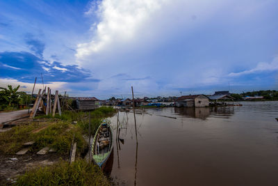 Buildings by river against sky