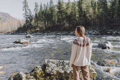 Woman at riverbank in forest sunny day