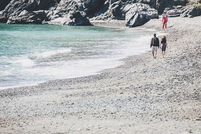 Rear view of people walking on beach