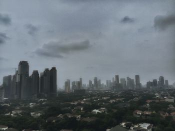 View of cityscape against cloudy sky