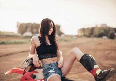 Midsection of young woman sitting outdoors