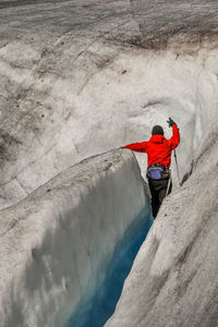 Rear view of man hiking on ice formations