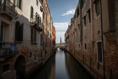 Canal amidst buildings in city against sky