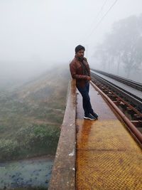 Full length of young man on railroad track against sky