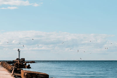 Seagulls flying over sea against sky,coastal lighthouse element, signs, light