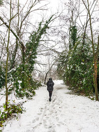 Rear view of person walking on footpath during winter